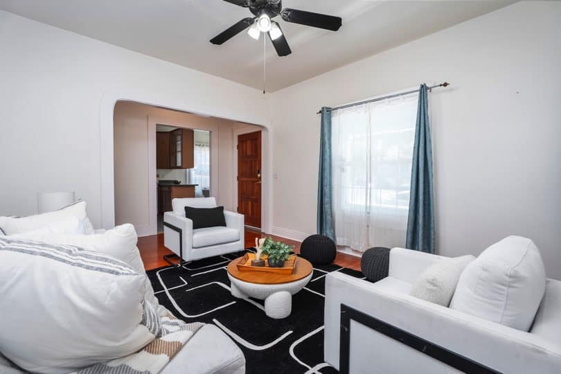 A living room with white chairs, a coffee table, and an arched doorway leading to the entrance at 1932 C Street in Golden Hill.