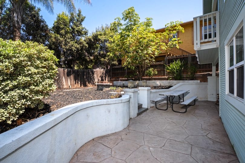 A stone patio with built-in retaining walls and a picnic table overlooks the terraced backyard at 1932 C Street in Golden Hill.