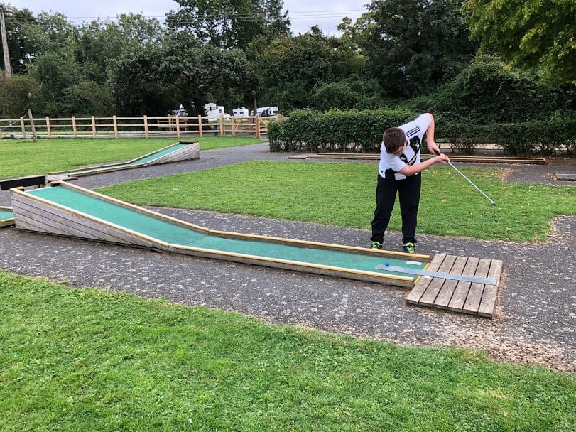Teenage boy playing mini golf