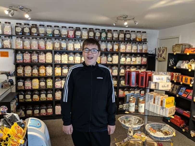 Teenage boy standing in a sweet shop with a smile on face
