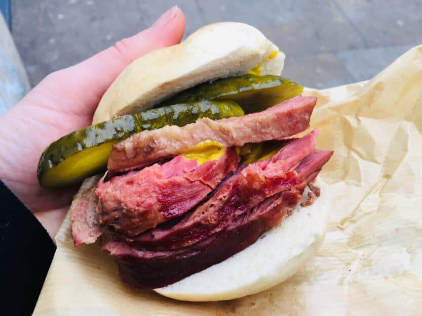 Bagel from Beigal Bake in London, England White bagel with pink salt beef and green gherkin in a white from Beigal Bake in London, England