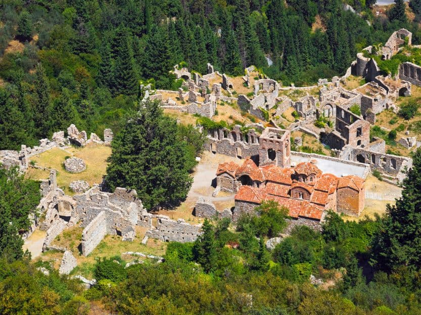 Ancient Town of Mystras View from above of the ancient town of Mystras. Mainly grey stone ruined wallks and fortifications and a church wtith a red tiled roof. Surrounded by green evergreen trees.