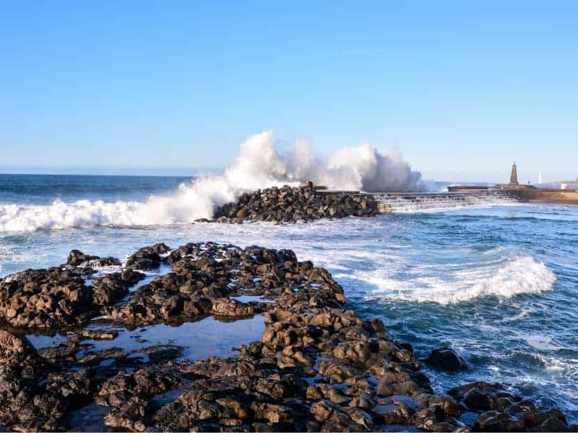 Bajamar Village Natural Pool Bajamar Village. Image of natural swimming pool with rocks in the foreground and crashing waves and blue sky in the background