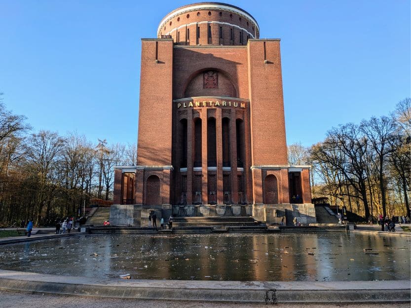 Hamburg Planetarium Red brick Hamburg Planetarium with blue sky behind and iced over pond in front.