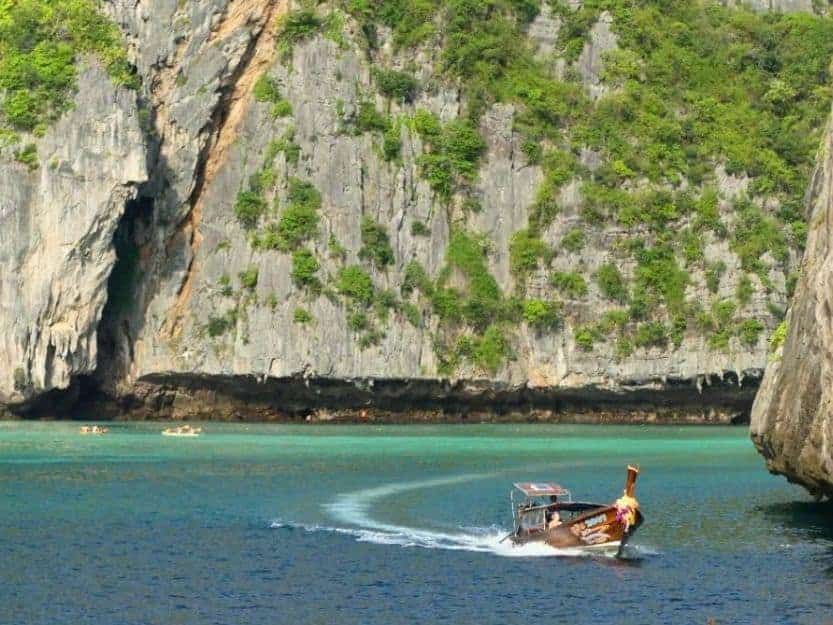 Longtail Boat from Krabi to Railay Beach in Thailand Longtail boat travelling near limestone cliffs between Krabi and Railay beach in Thailand.
