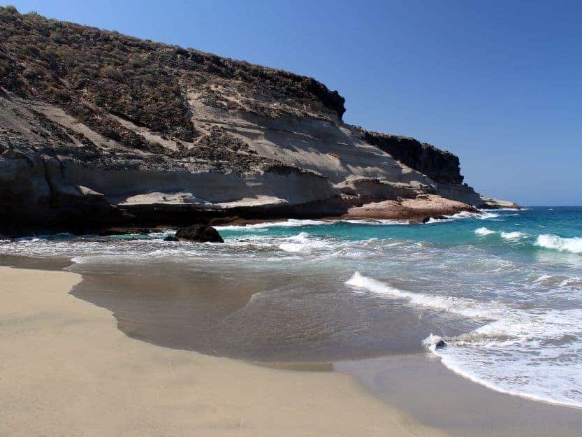 Playa Diego Hernandez Playa Diego Hernandez, image of sandy bay on the left with cliffs on the left and blue sea on the right
