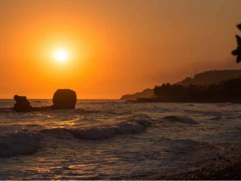 Sunset at Playa El Tunco Sunset at Playa El Tunco, orange sunset behind pig rock. With hills in the background and waves crashing on the rocks in the foreground.