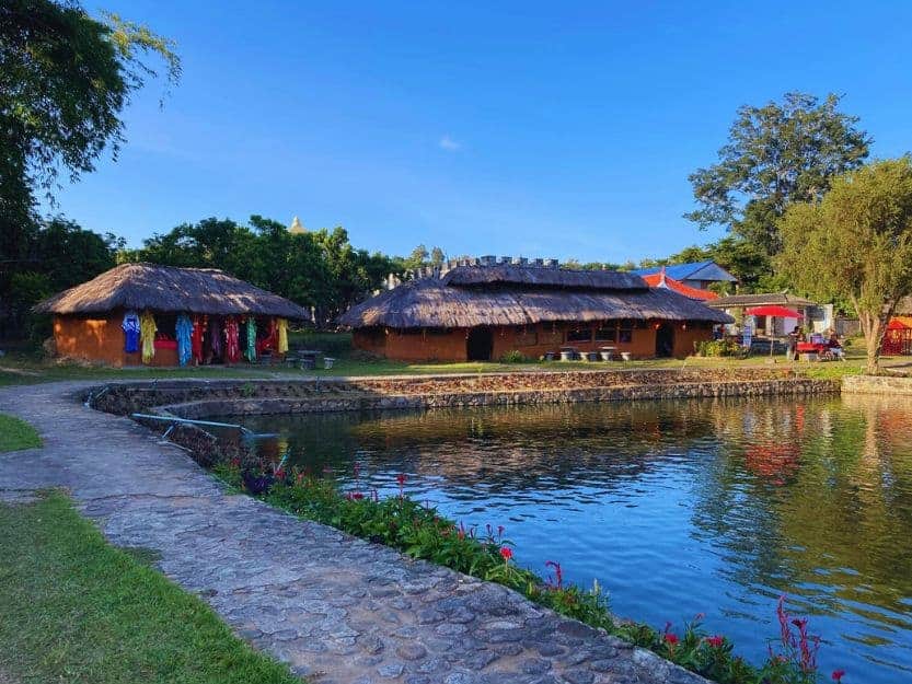 Santichon Village (Chinese Village) in Pai Santichon Village (Chinese Village) in Pai, Thailand. Traditional clay houses on the waters edge with a paved path around edged with green grass.