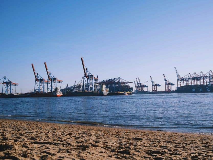 Secret Beach at Elbstrand in Hamburg Secret Beach at Elbstrand in Hamburg. Sandy beach in foreground with huge container ships and cranes in the sea in the distance
