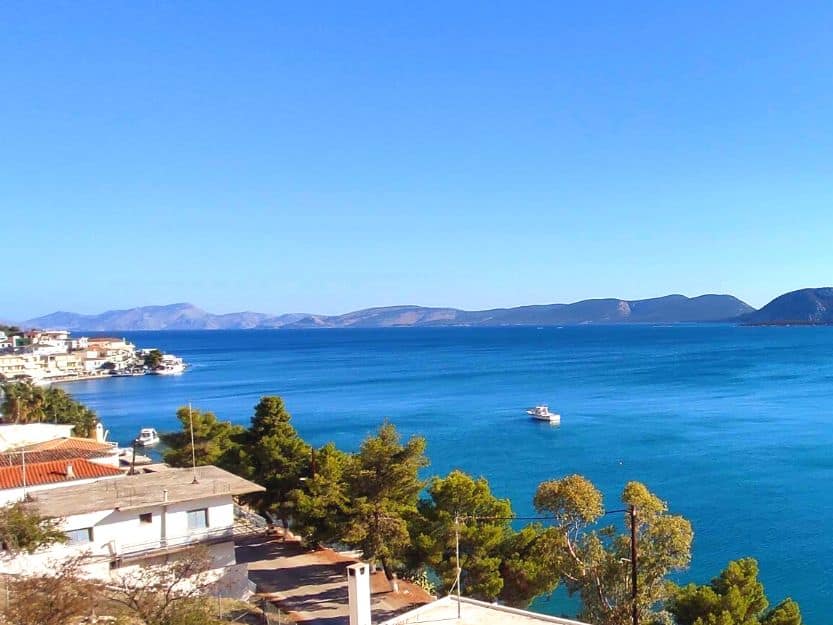 View from Grand Bleu Apartments in Ermioni Greece. View of Madrakia side of Ermioni, Greece from Grand Bleu Apartments. Blue sea, green pines and the port side.