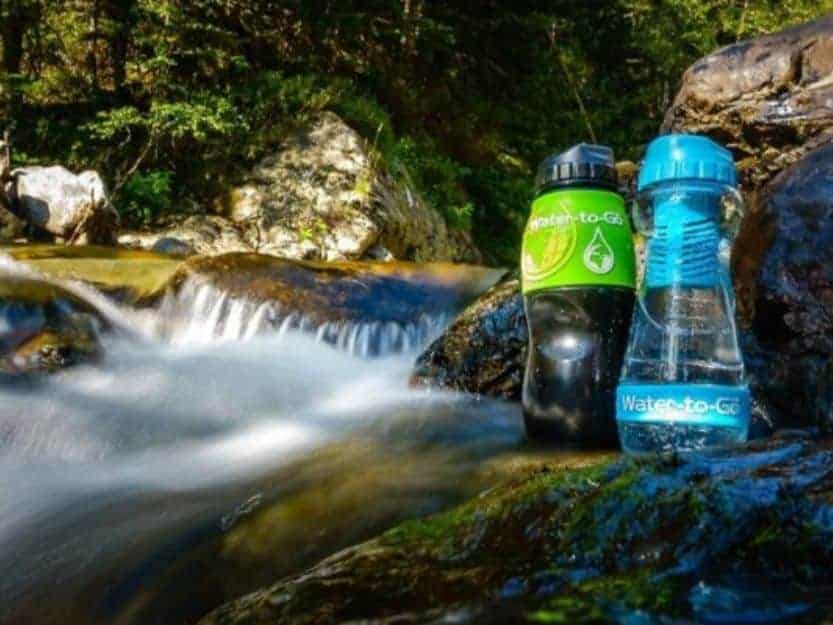 Water-to-Go Filter Water Bottles Water to Go Filter Water Bottles Big green and black bottle with small blue one in a river.