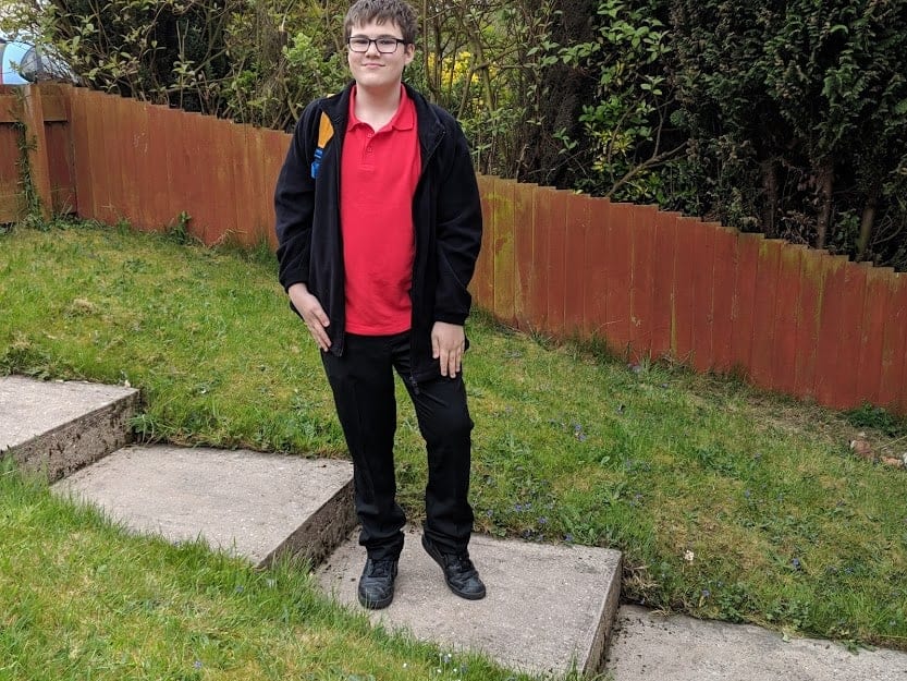 Ben standing on some steps, wearing black trousers and a red t-shirt