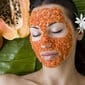 In image of a young woman with pieces of papaya all over her face as a face mask
