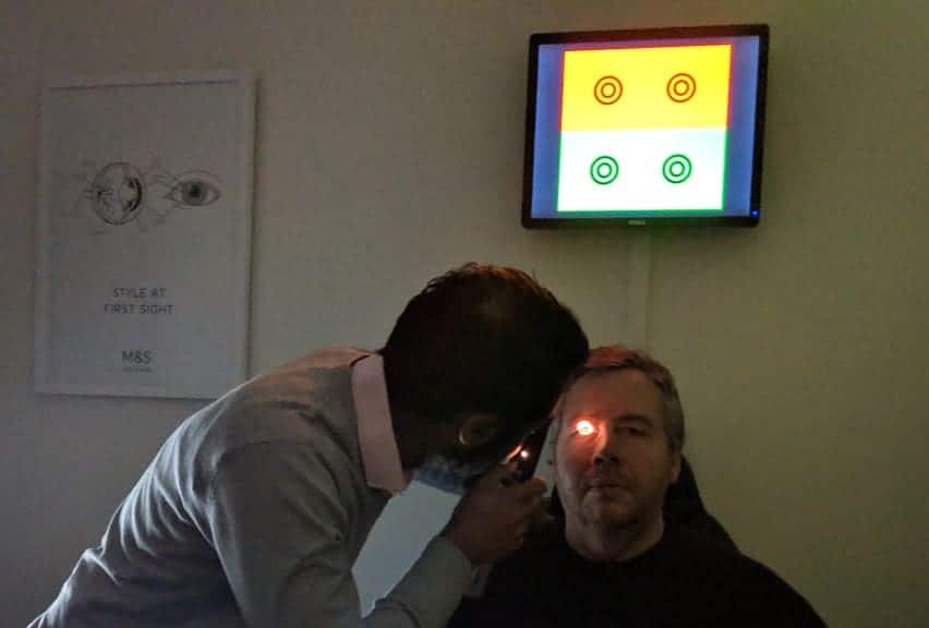 An optician waving a light into a gentlemans eye