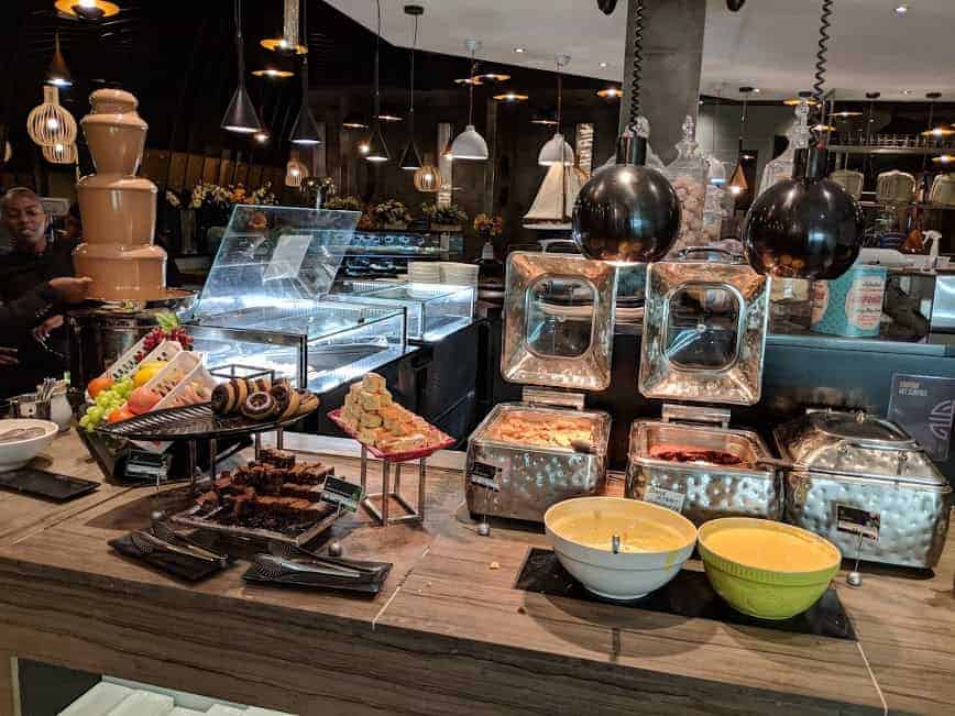 chocolate fountain to left with fruit, custard and cakes all in servers