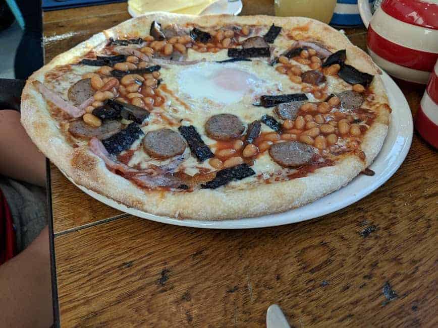 breakfast pizza with eggs beans and sausage on the top.