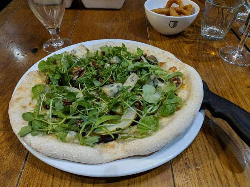 pizza topped with fresh rocket on a white plate.
