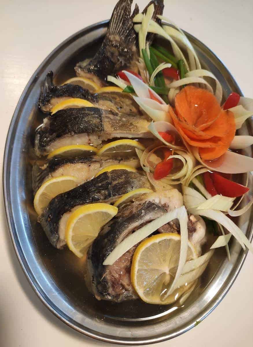 Carp with veggies in a steel dish.