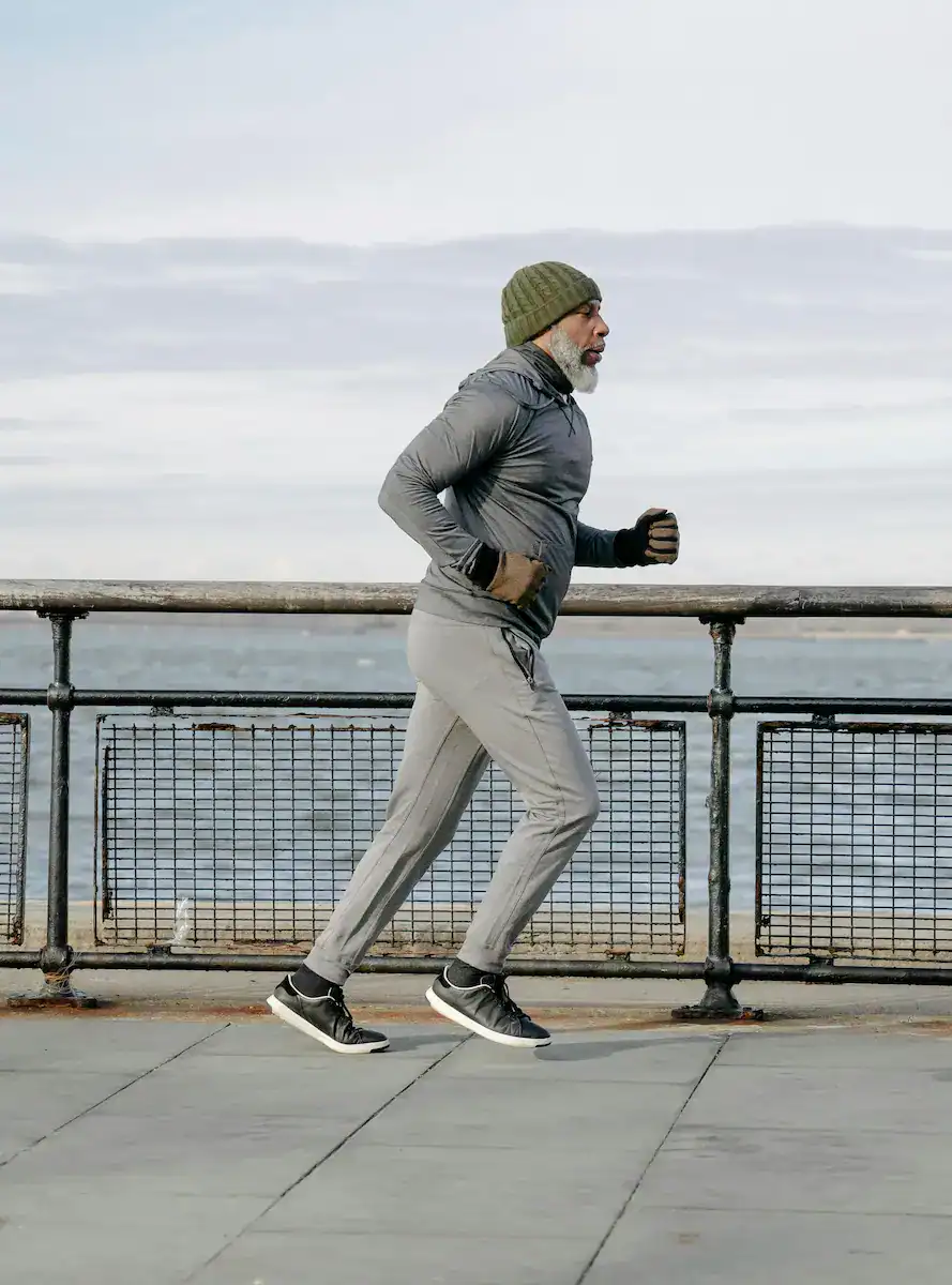 older man with good posture running along a seafront pavement