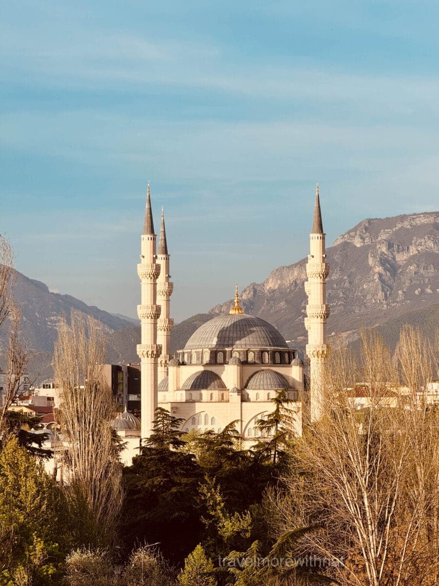 A cream and blue-domed Mosque stands in front of mountains in the distance, as seen from the top of Tirana Pyramid. Climbing to the top should not be missed during your walking tour of Tirana.