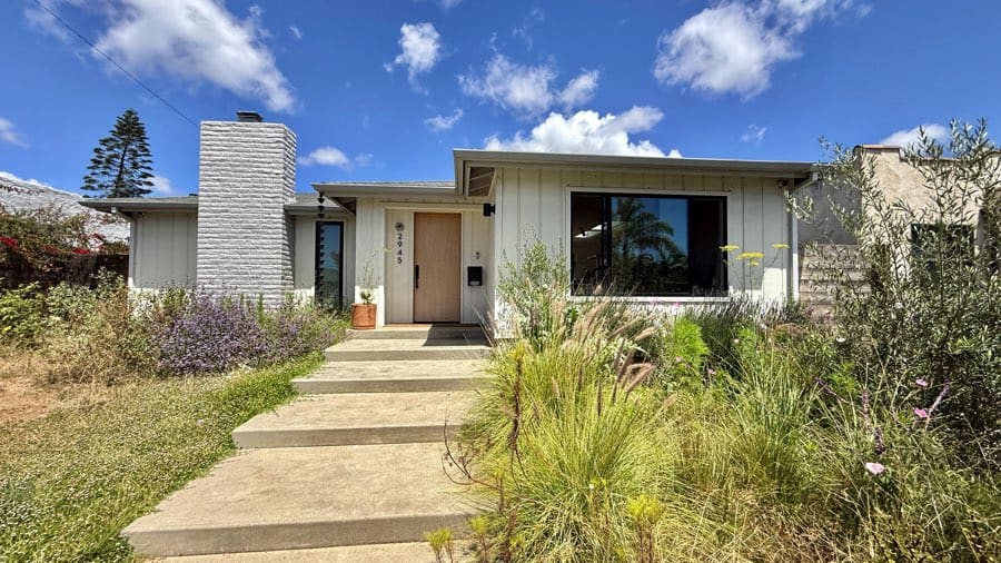 Single-story North Park San Diego home with a front walkway, chimney, large window, and drought-tolerant landscaping under a sunny blue sky.