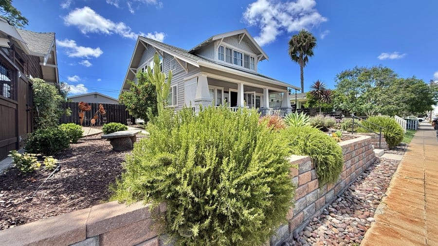 Craftsman-style home in North Park, San Diego, with a landscaped front yard, stone retaining wall, and palm trees