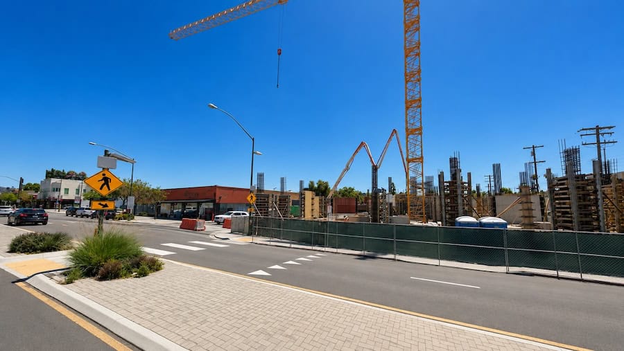 Construction site with tower crane along University Avenue near Pershing Street in North Park, San Diego, on a sunny day.