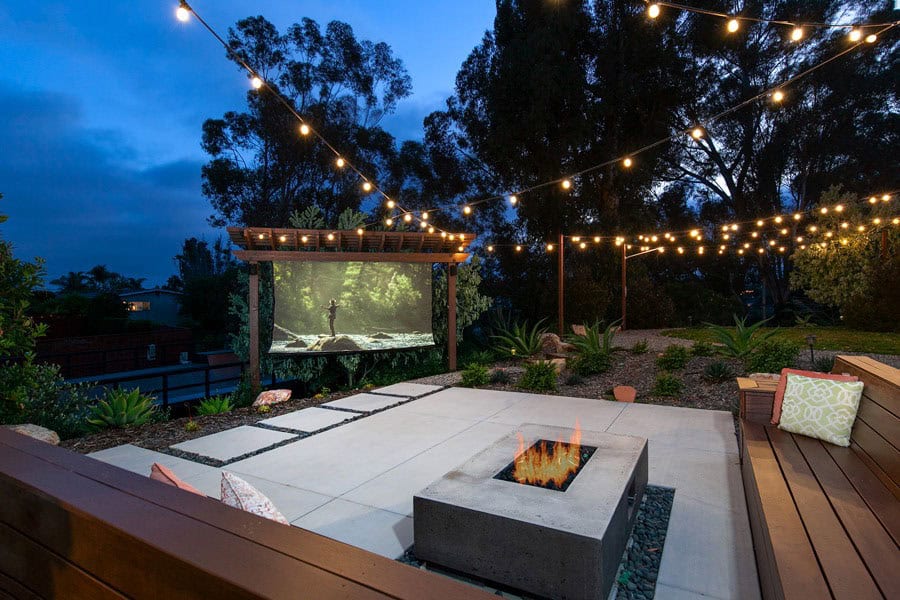 A Backyard Evening View with seating area, Movie Screen, and white hanging lights above