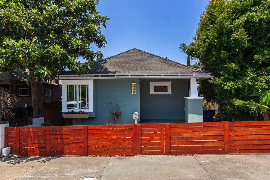 front of 920 Glendale Av, a green colored bungalow with red stained fence