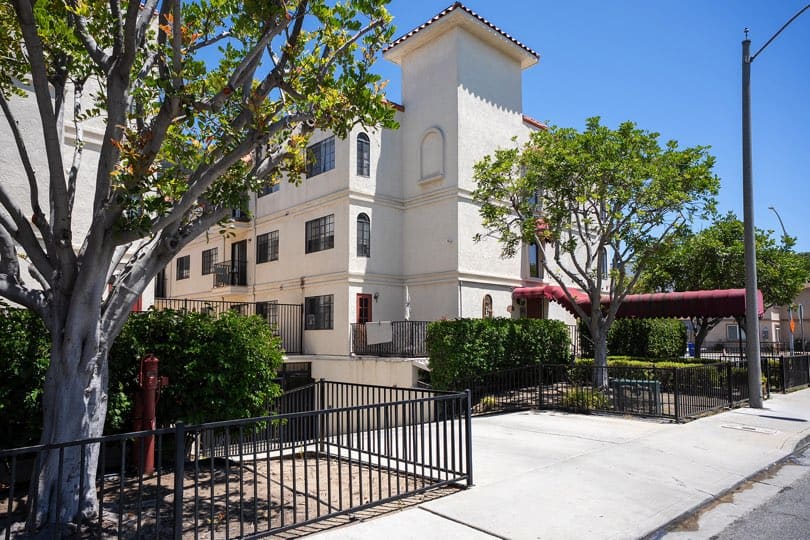 Exterior view of a multi-story stucco condo building with red tile roof accents, a covered walkway canopy, and front fencing at 205 Ohio St Unit 304 in North Park.