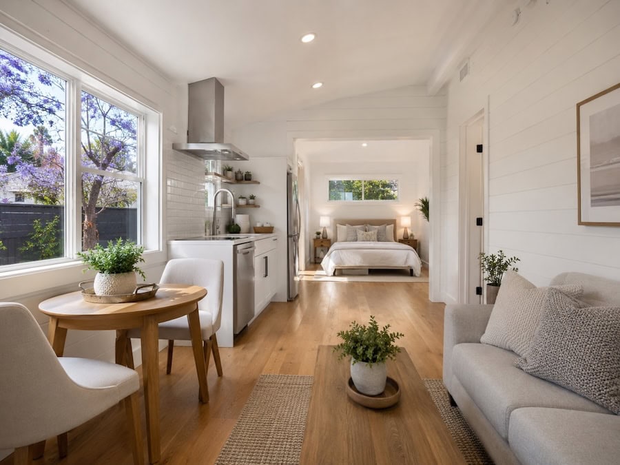 Modern San Diego ADU interior with white shiplap walls, oak floors, compact kitchen, dining nook, and bedroom view.