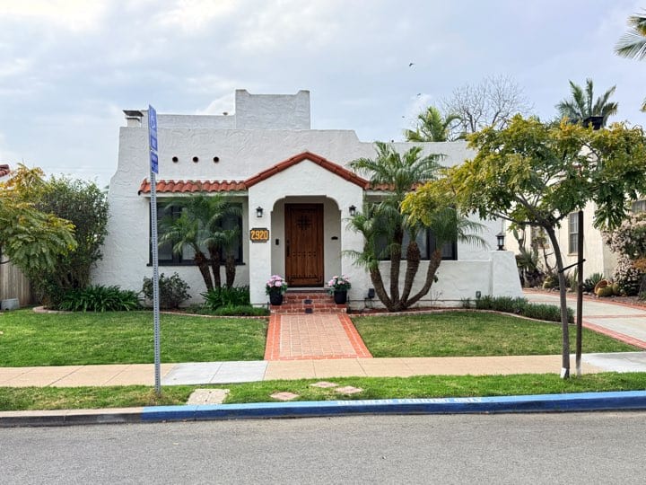 White Spanish-style home in North Park, San Diego, with a red tile roof, arched entry, palm trees, and landscaped front yard.