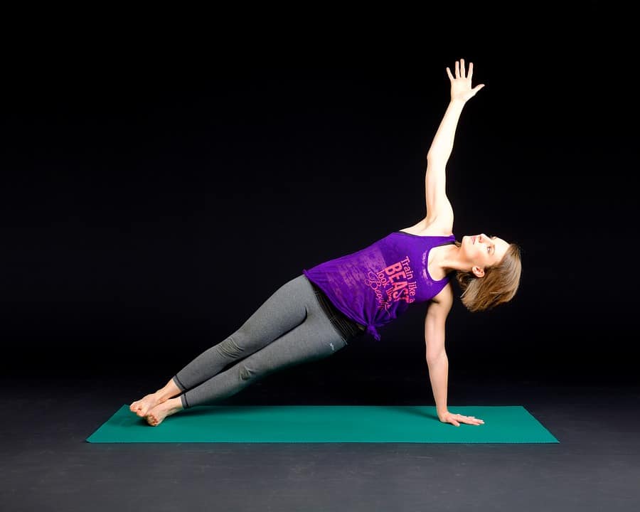 woman doing yoga on a green mat with a dark background