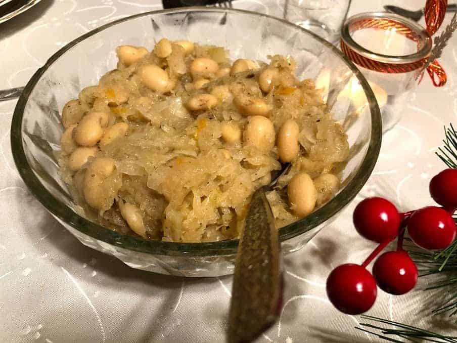 A bowl of white beans and sauerkraut, a classic Polish dish, on a table.