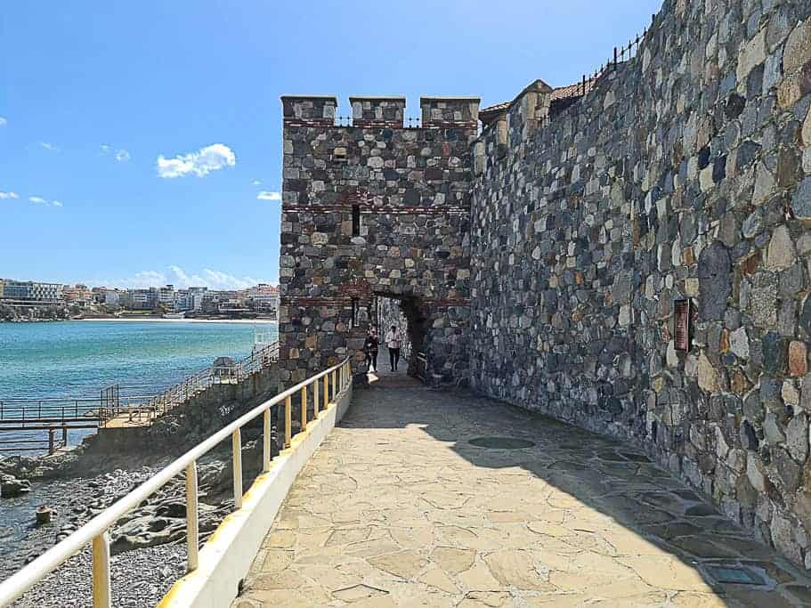 Sozopol's fortified stone walkway leading to a robust gatehouse by the sea.