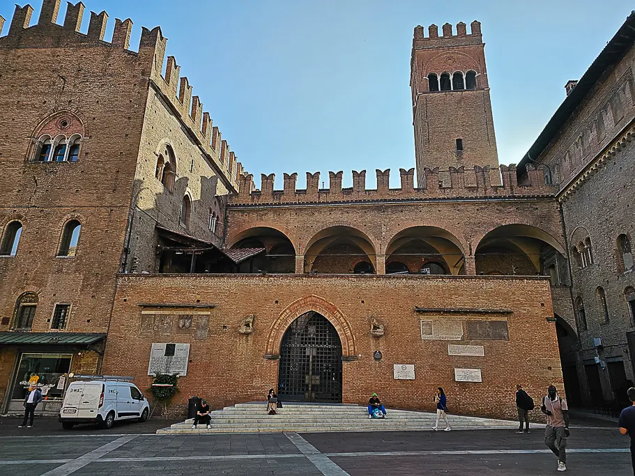 Fortress-like Palazzo Re Enzo seen from Piazza del Nettuno, a must-see medieval palace in Bologna, known for its battlements and open loggia.