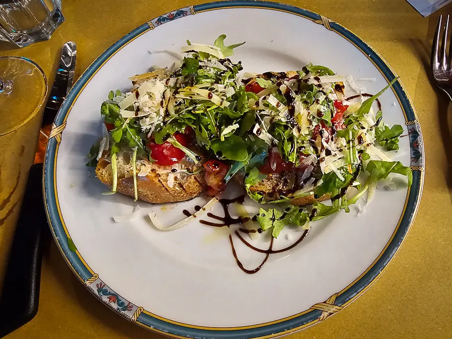 Fresh bruschetta topped with arugula, tomato, Parmigiano and balsamic glaze—a tasty reason why Bologna is worth visiting for authentic Italian cuisine.