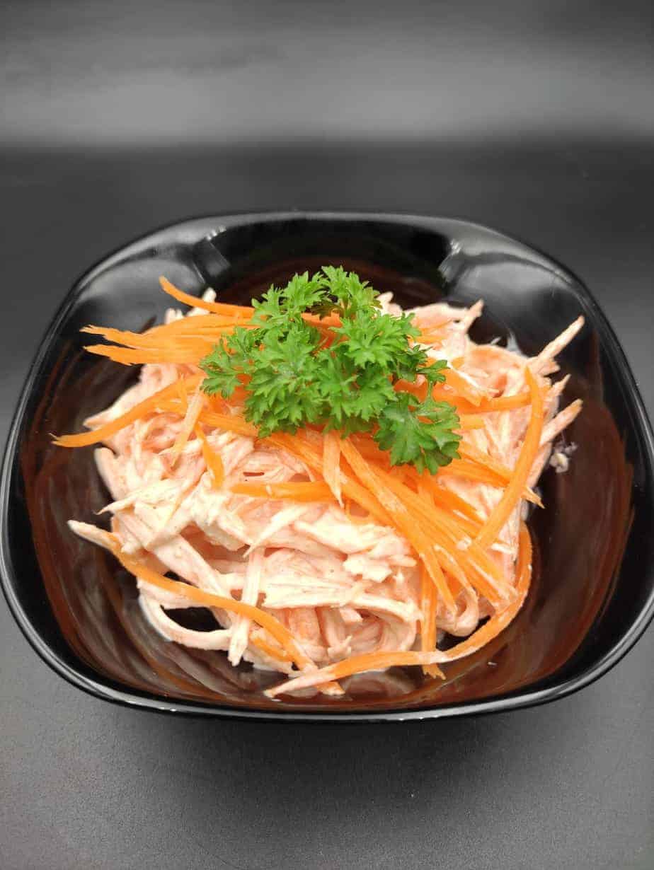 Polish surowka z marchewki polish carrot salad in a black bowl.