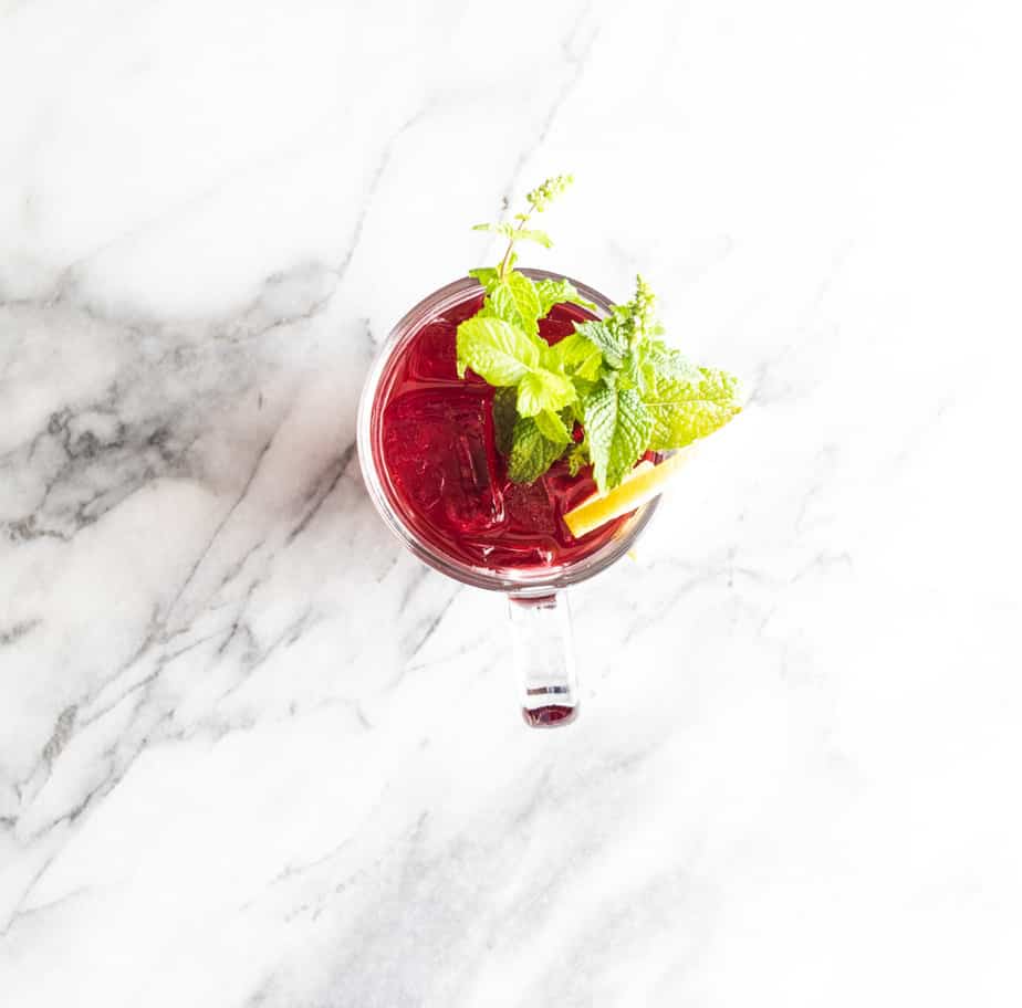 Lemon slice, mint flowers in a cranberry vodka cocktail.