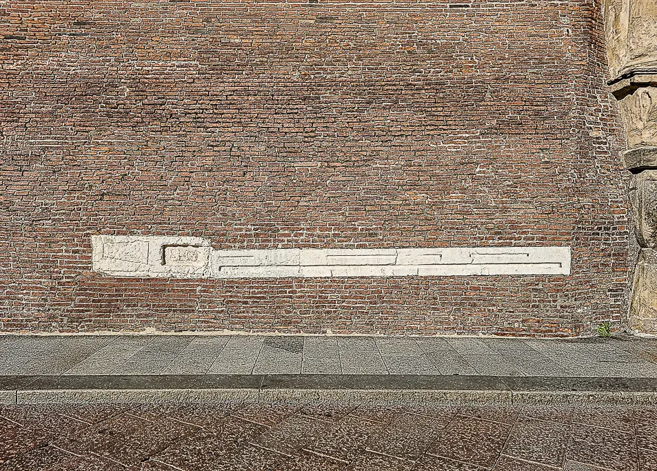 Stone carvings showing Bologna’s historic units of measurement embedded in the wall of Palazzo d’Accursio—an overlooked detail perfect for historical and educational travel photography.