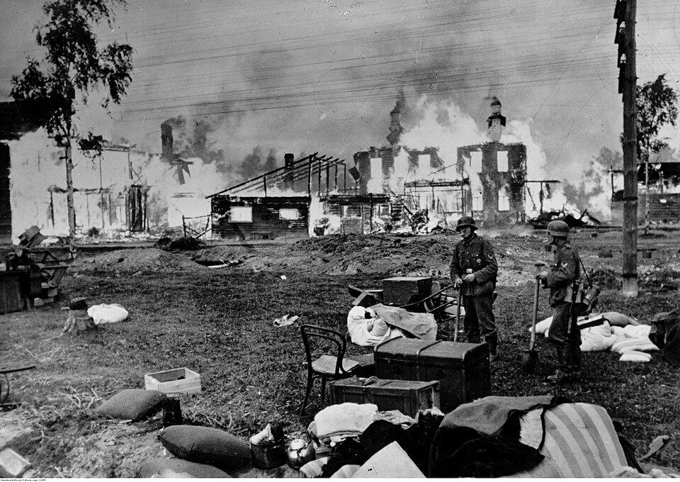 Duitse troepen bij de buitenwijken van Leningrad, met achtergelaten huisraad en een brandende kerk op de achtergrond, 1941.