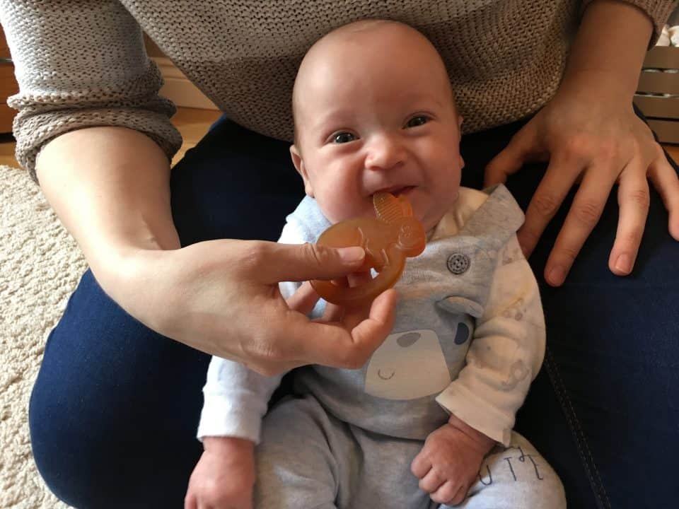 teething baby smiling whilst chewing on the rooba rabbit