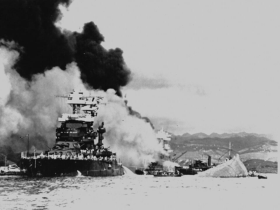 USS Maryland en gekapseisde USS Oklahoma na de aanval op Pearl Harbor, met zicht op schade aan Battleship Row.