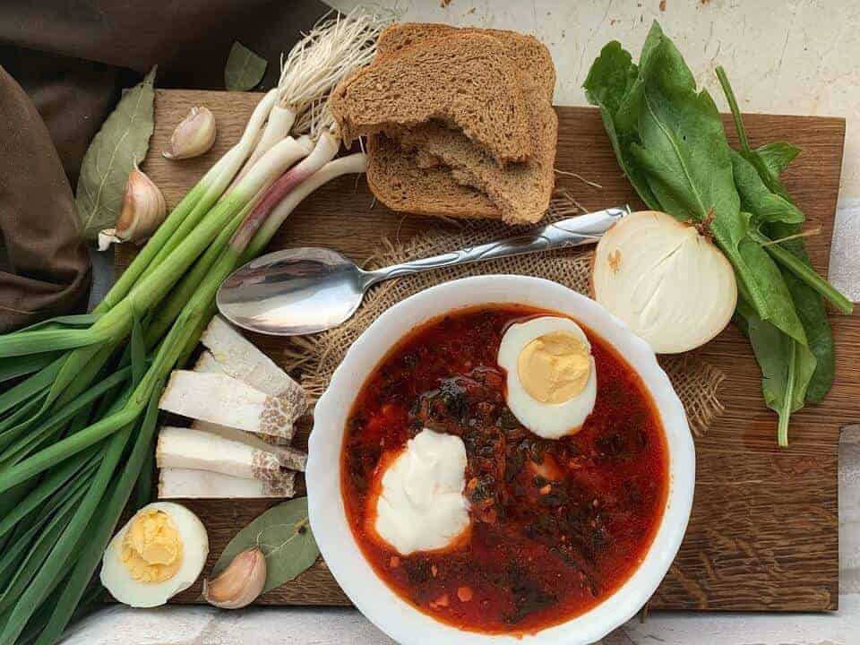 Red borscht soup with the ingredients around it.