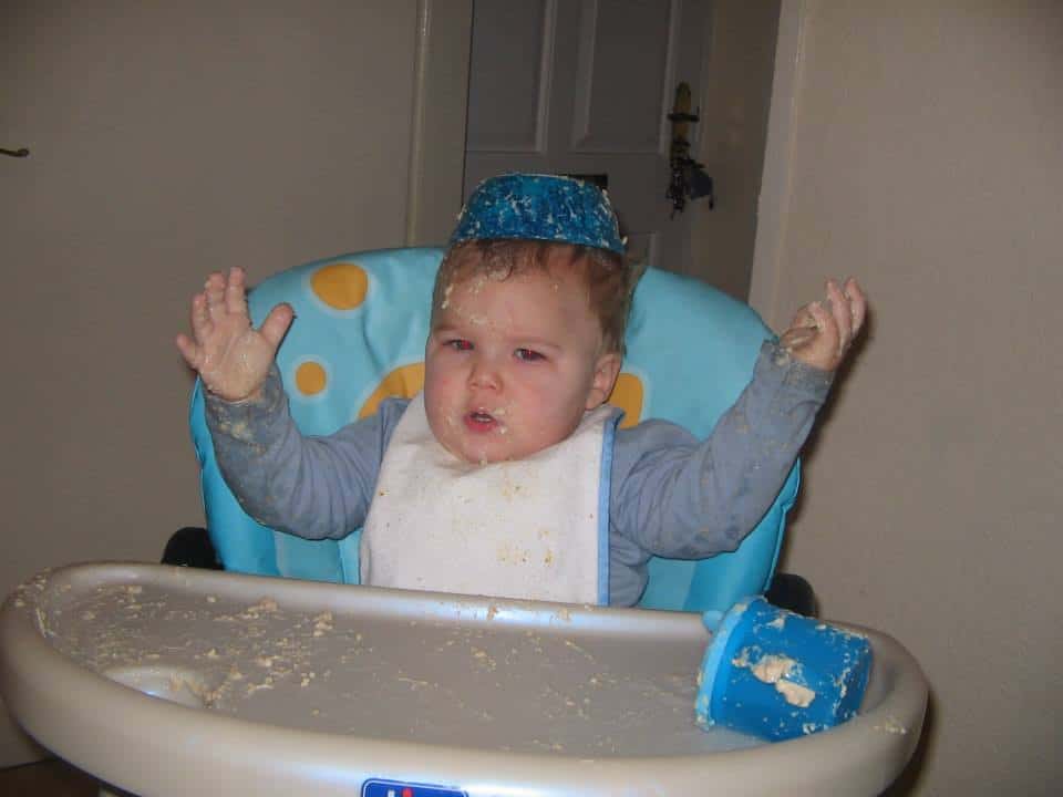 A baby sitting in a highchair with food on their head