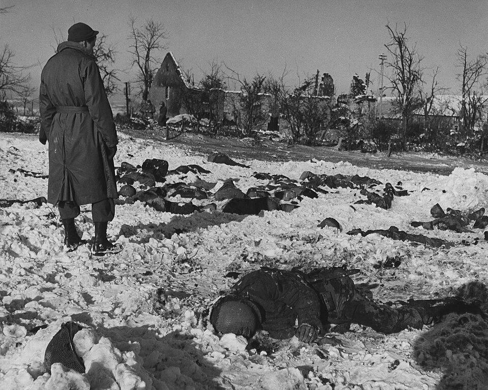Amerikaanse soldaat bekijkt slachtoffers van het Malmedy-bloedbad, 17 december 1944, waar 84 krijgsgevangenen door de Waffen-SS werden vermoord.
