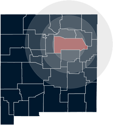 Navy blue county map of New Mexico with San Miguel County highlighted in red with area map circles, illustrating Grano Law Offices, P.C.'s areas of service. In general, Grano Law Offices, P.C. serves clients within 75 miles of Las Vegas, NM.