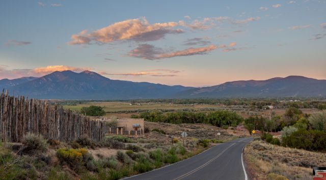 "A picturesque view of the New Mexico landscape at sunset, with a winding road leading towards distant mountains.