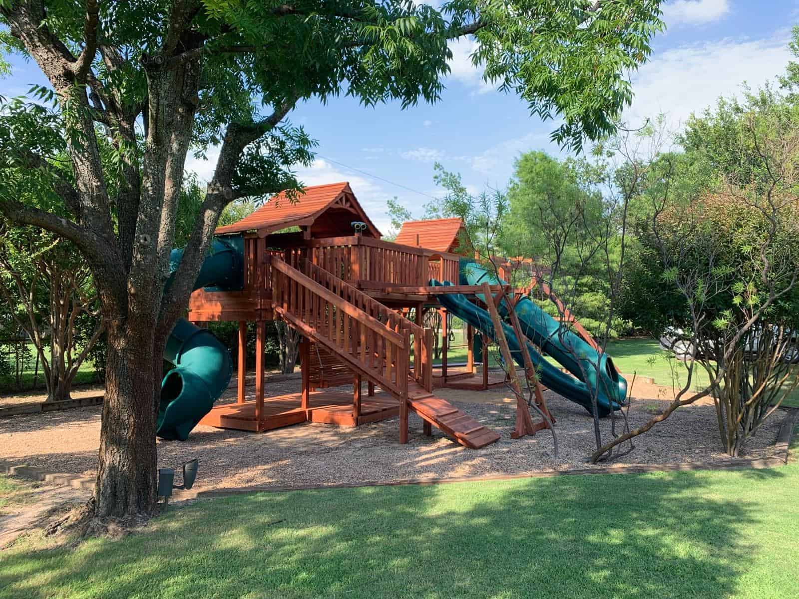 dalworthington gardens backyard swing set with green slides and boardwalk to with bridge to cabins