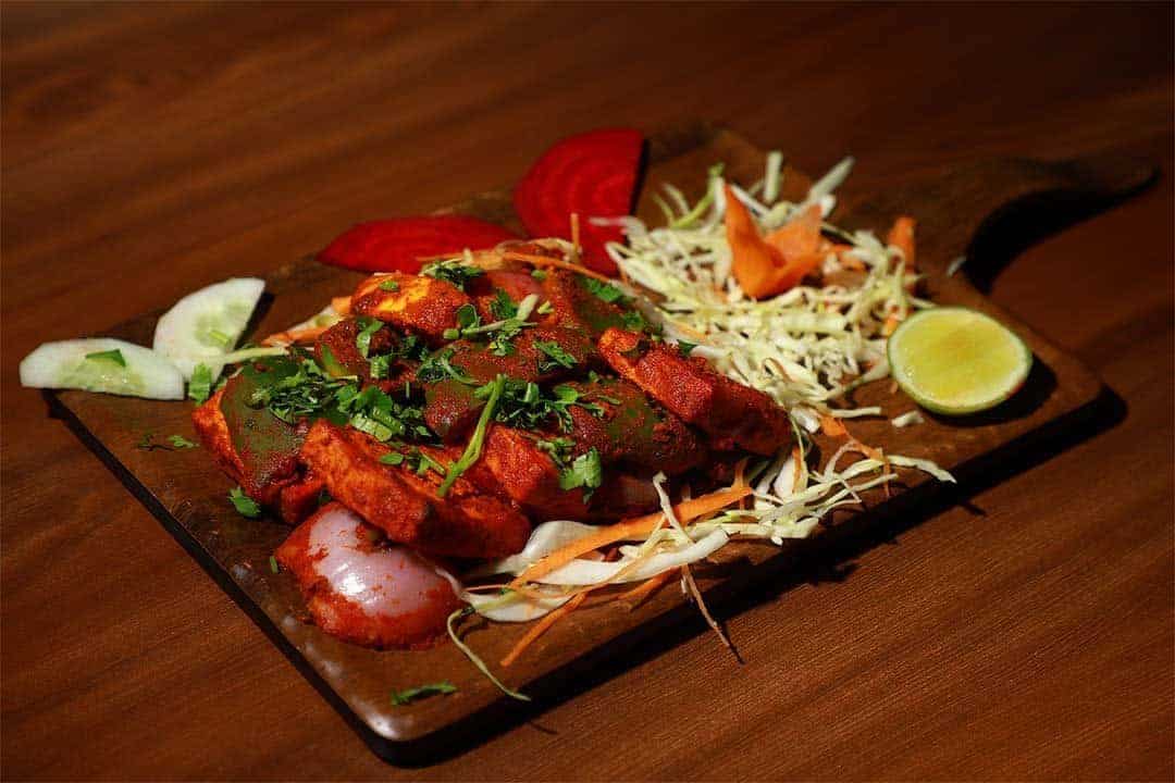 Juicy, flavorful chicken tikka served with fresh vegetables and lemon wedge at Biryani Place, a top destination for authentic Indian biryani and chicken dishes.